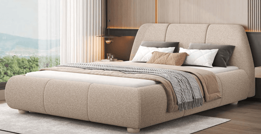 Beige upholstered bed with pillows and blankets in a modern bedroom setting.